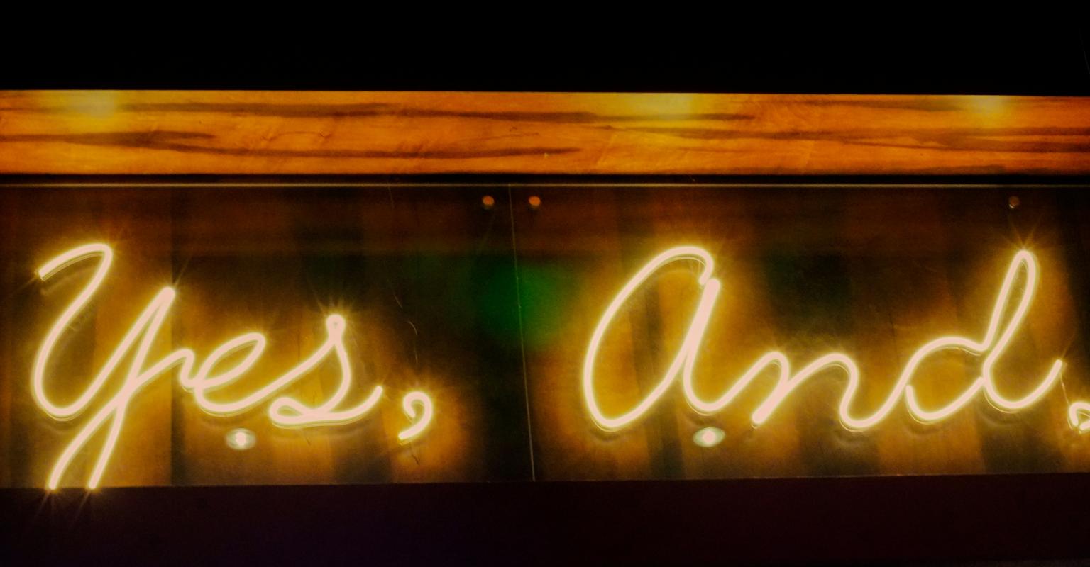 Neon sign saying "yes, and"