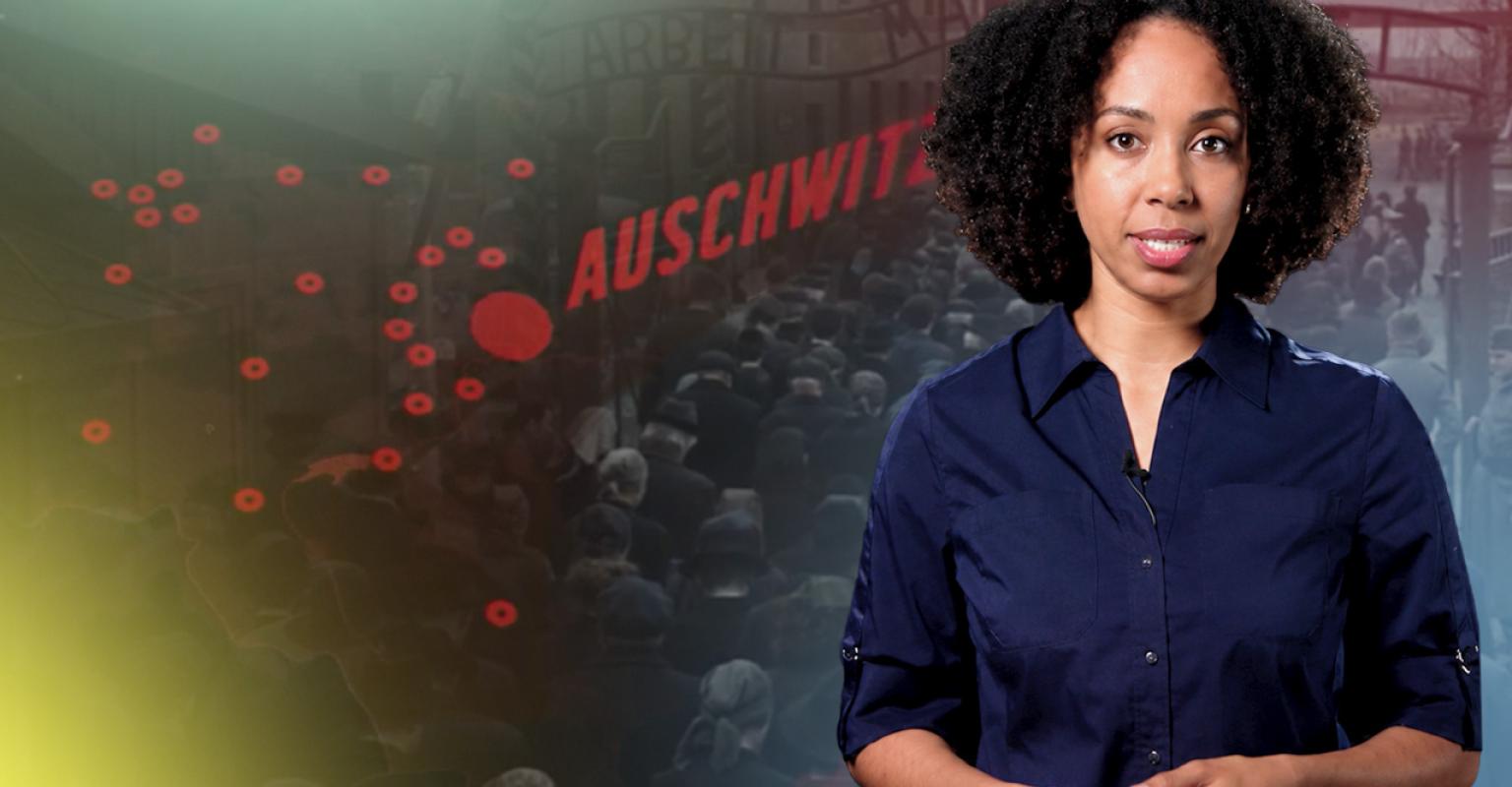 Woman in front of an image of the gate at Auschwitz