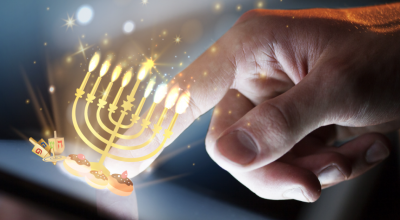 A hand tapping a virtual menorah sitting on a smart device