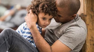 A dad holds and comforts his son