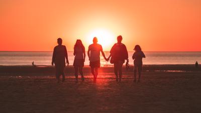 family walking on a beach at sunset 