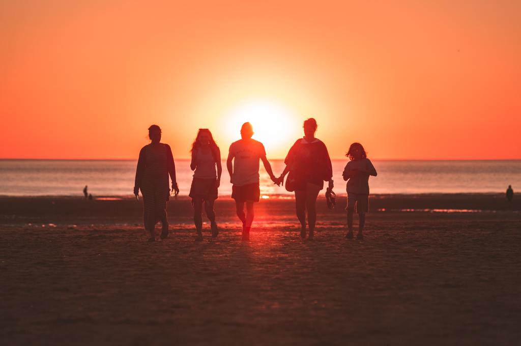 family walking on a beach at sunset 