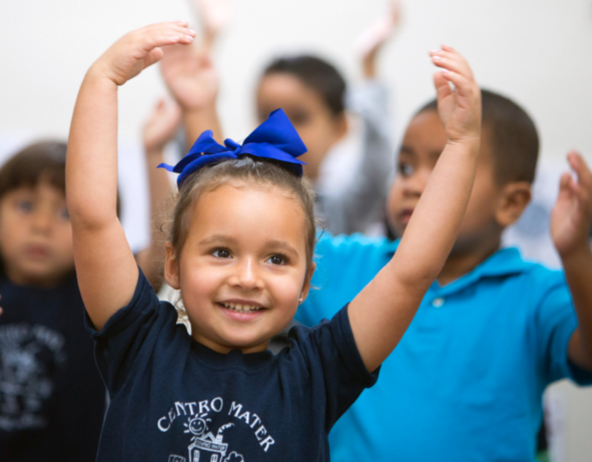 Smiling young child with hands raised in dancing position with other children