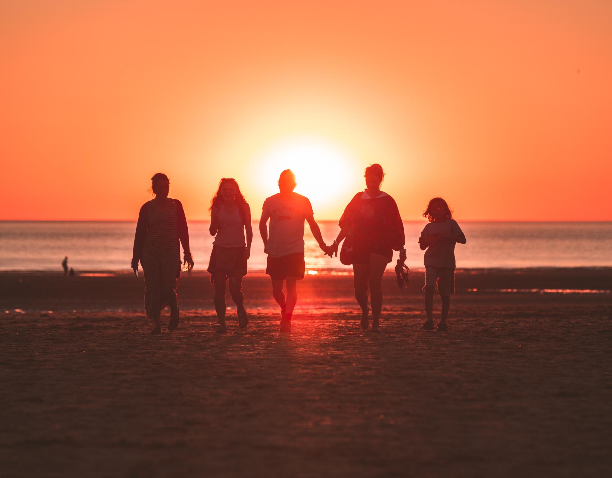 family walking on a beach at sunset 