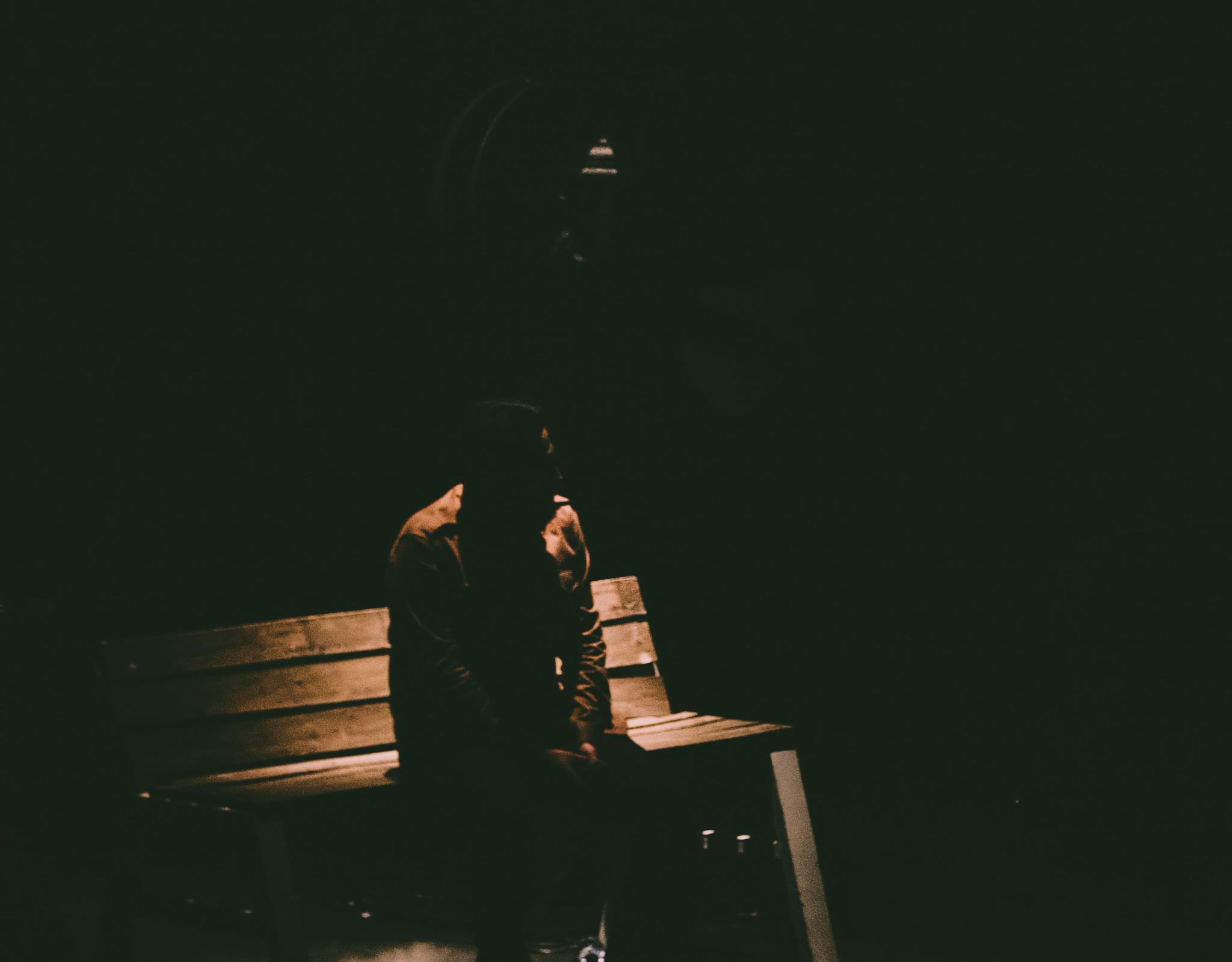 Person on bench in darkness 