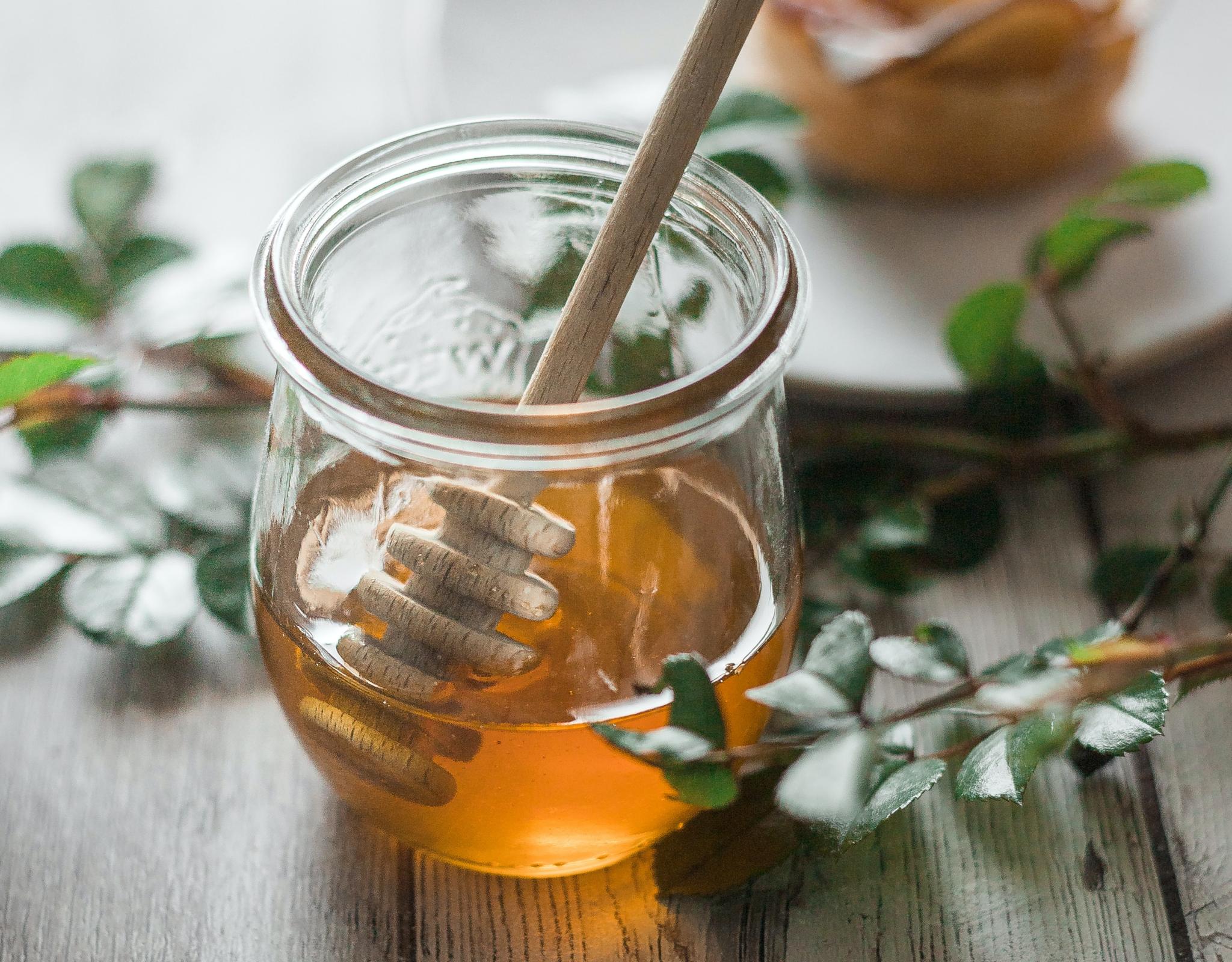 Pot of honey with apple pastry in the background