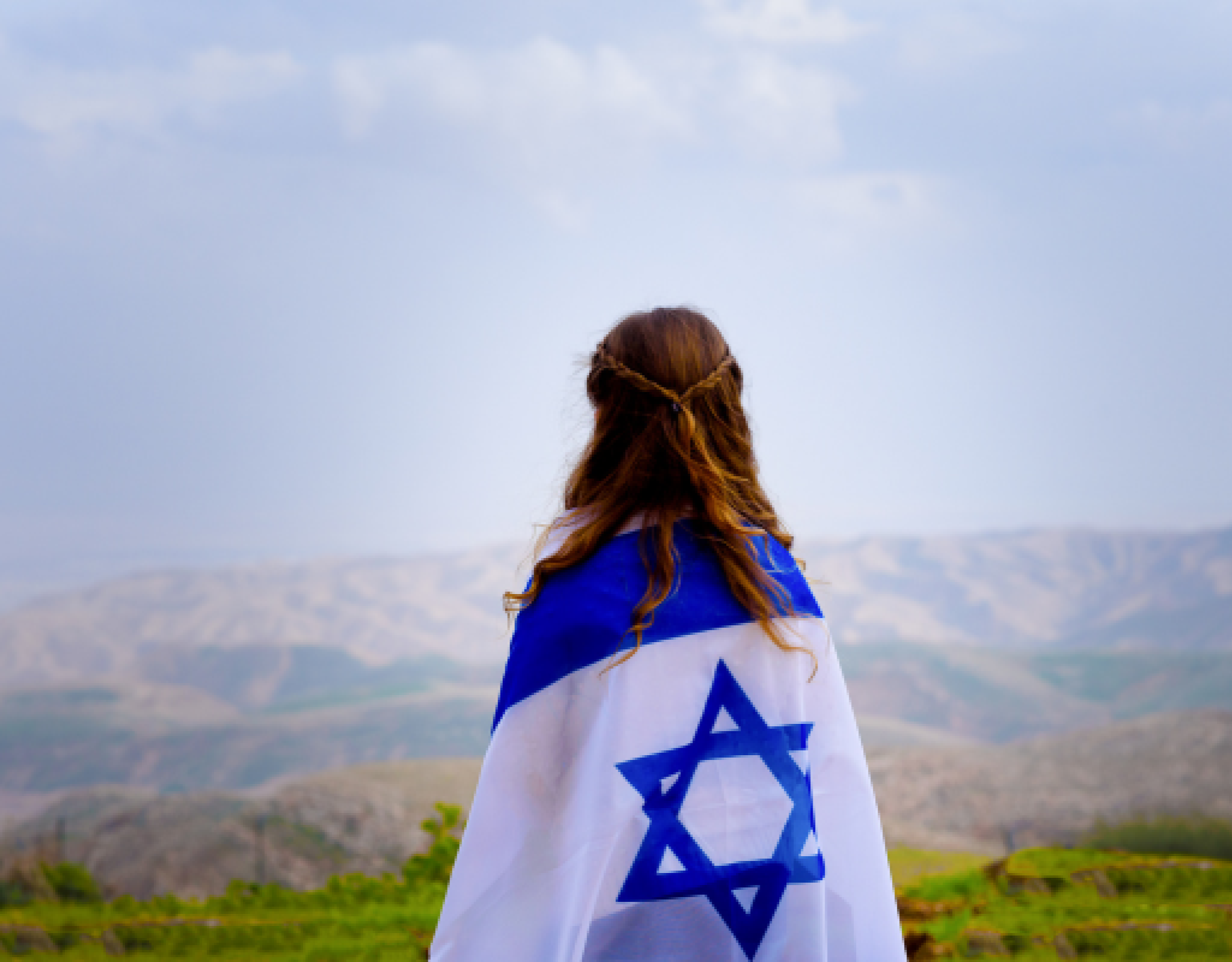 Girl with Israeli flag wrapped around her faces mountains