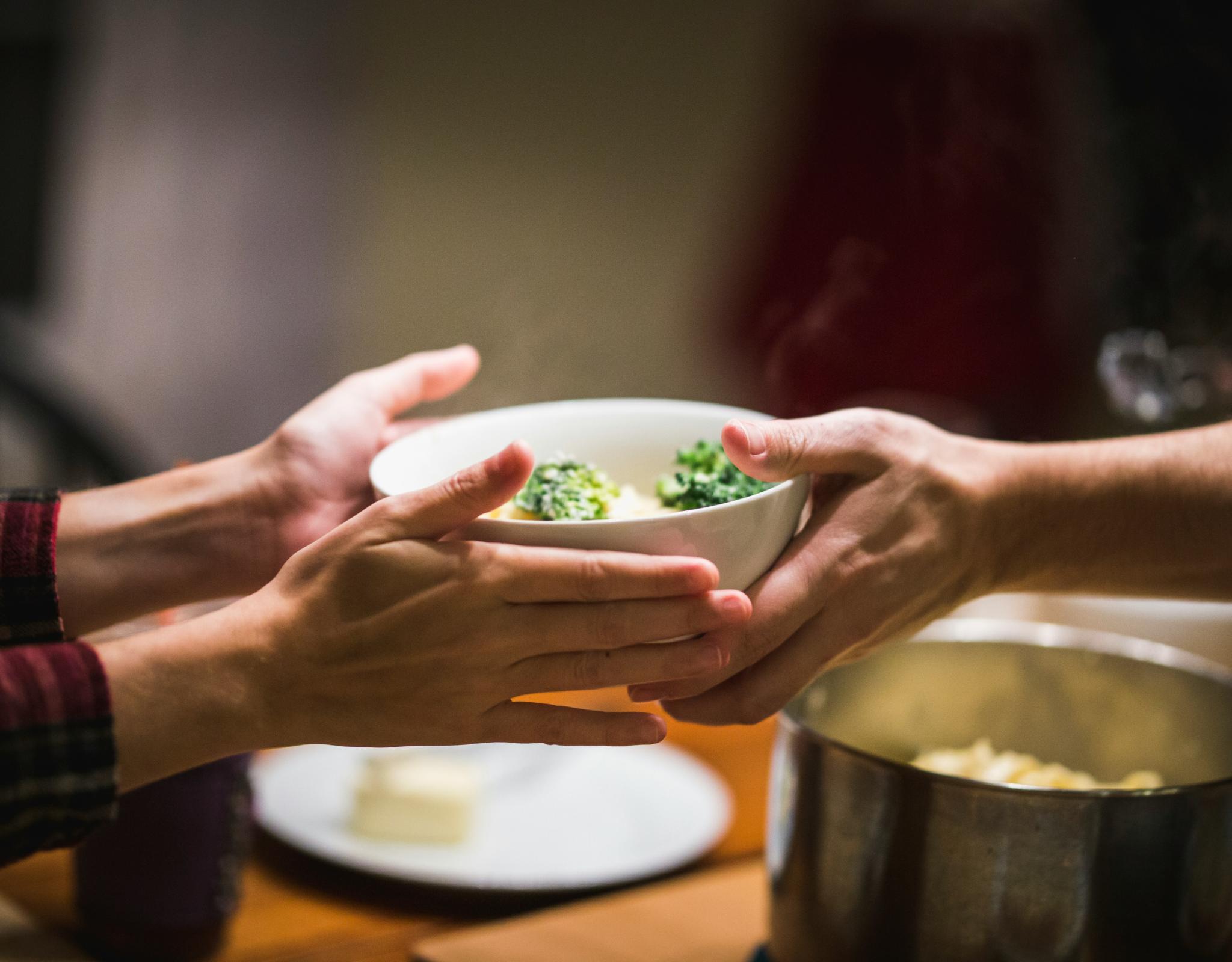 Bowl of food passing from one hand to another