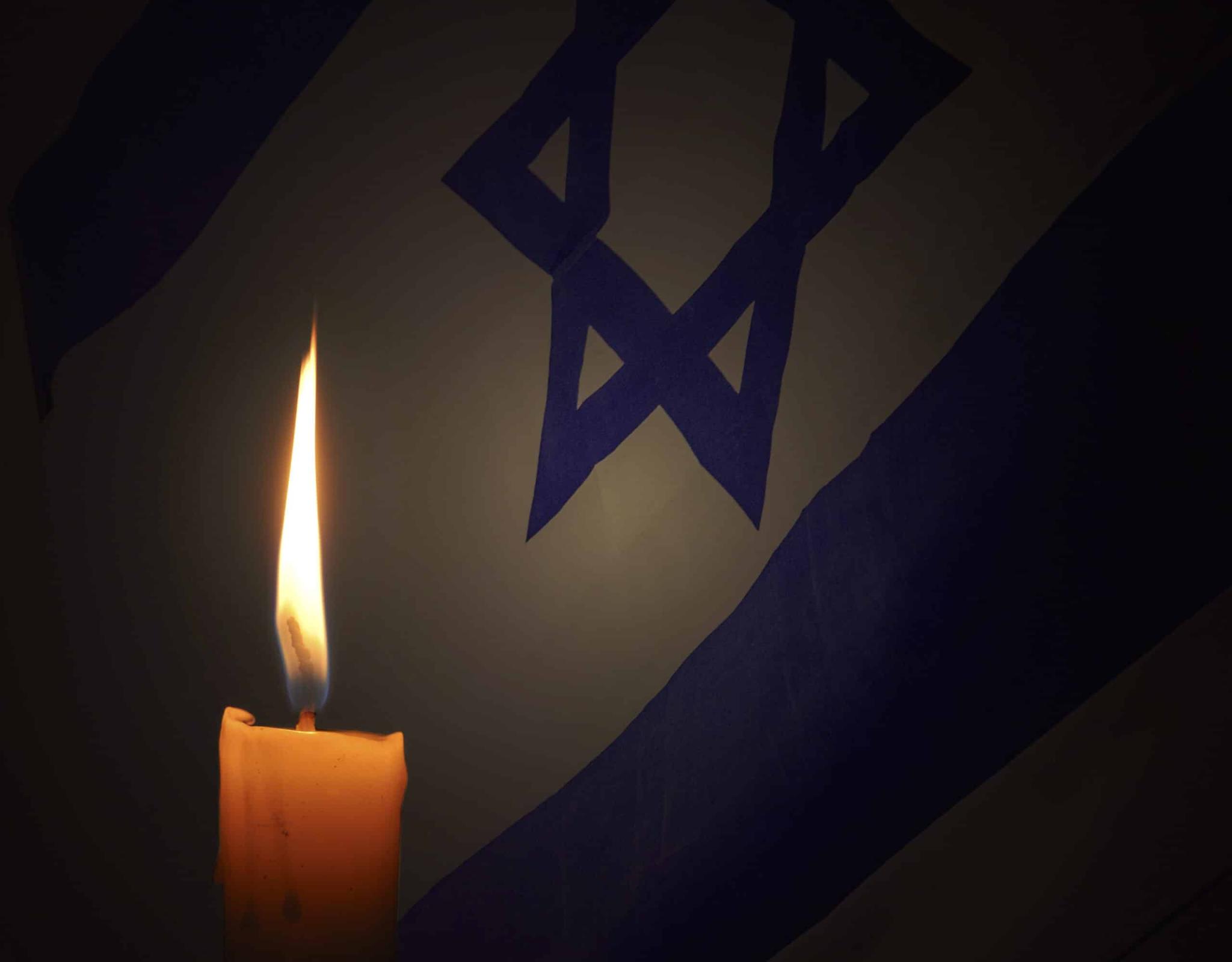 Candle burning in front of an Israeli flag
