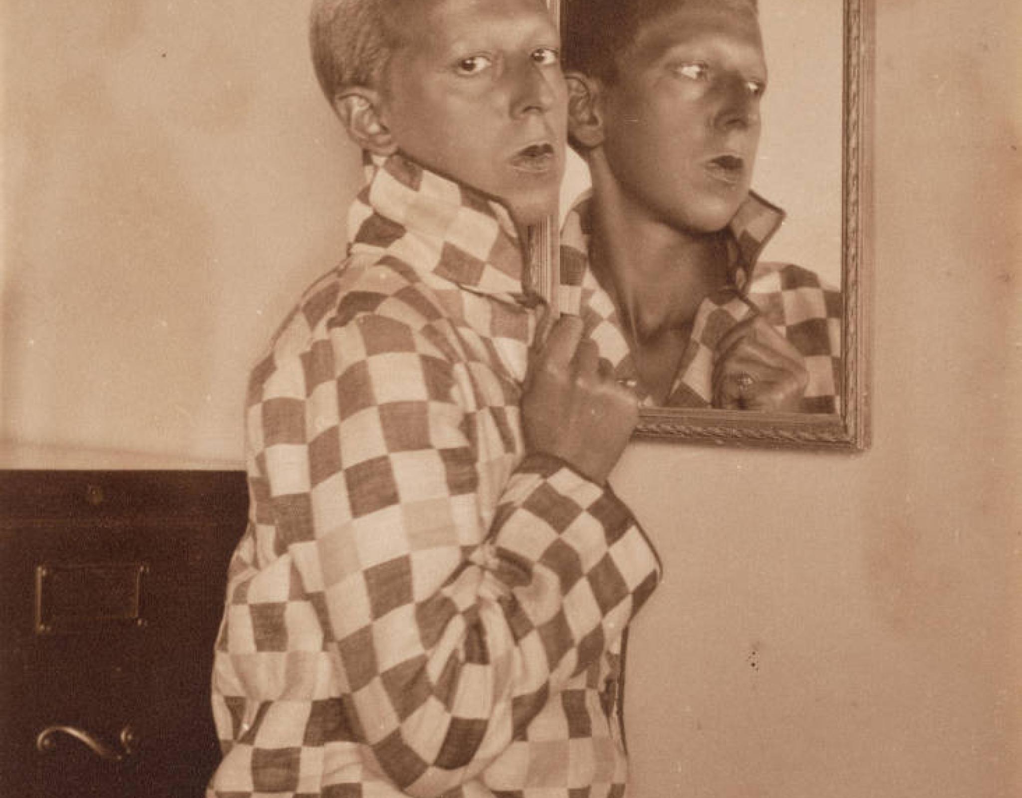 Claude Cahun standing in front of a mirror with reflection.
