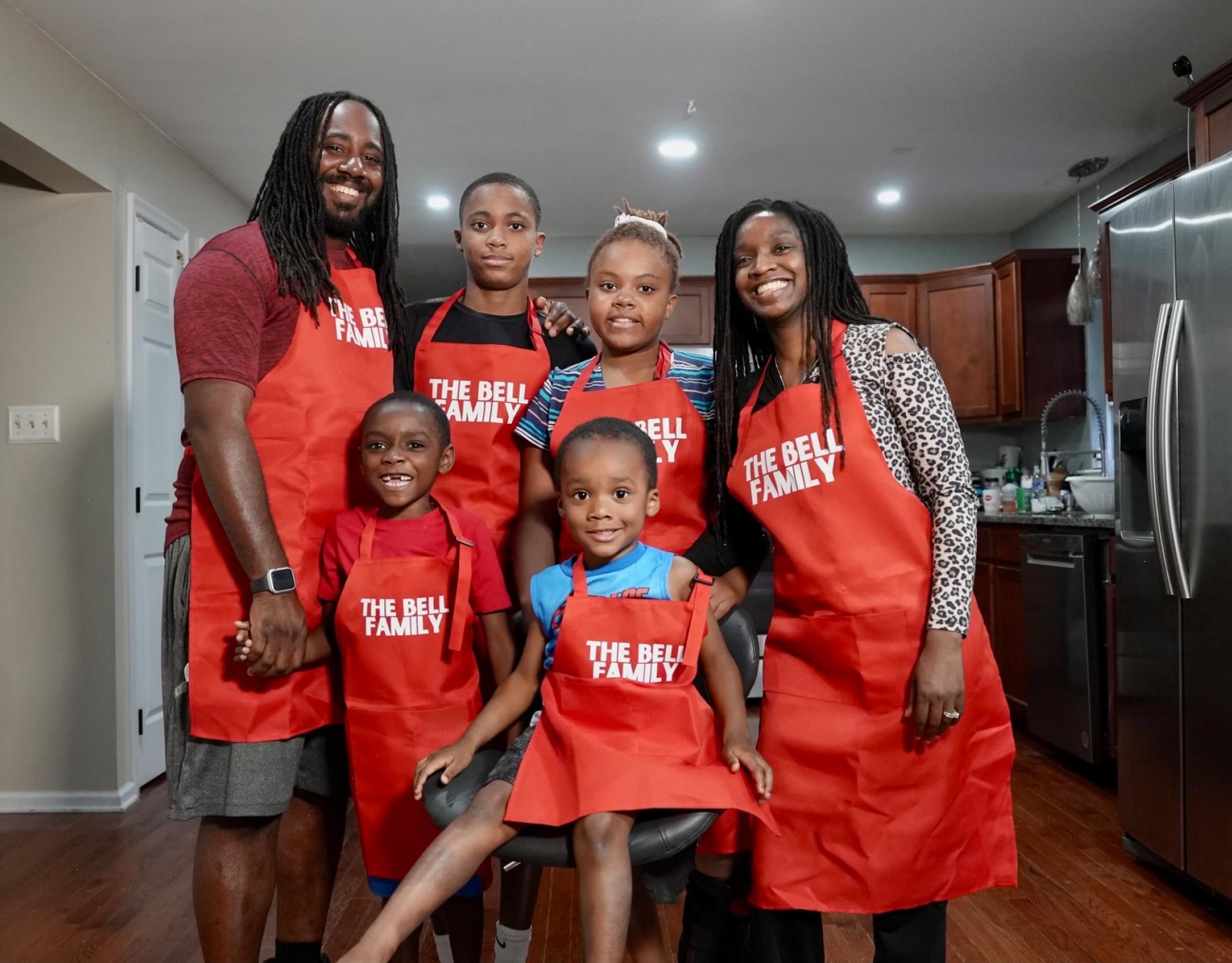 A photo of a family in aprons posing and smiling together.