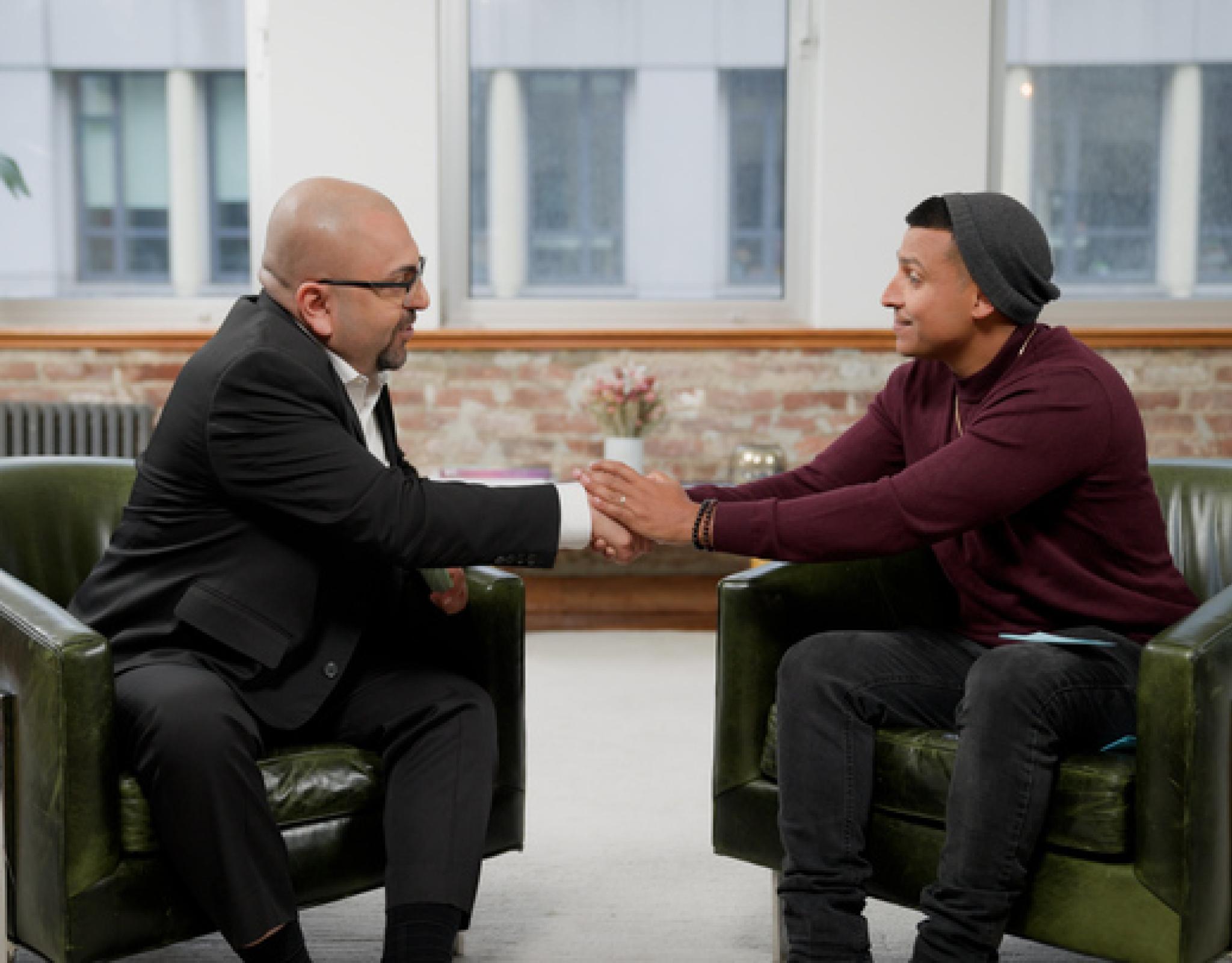 Two men in seated positions shaking hands