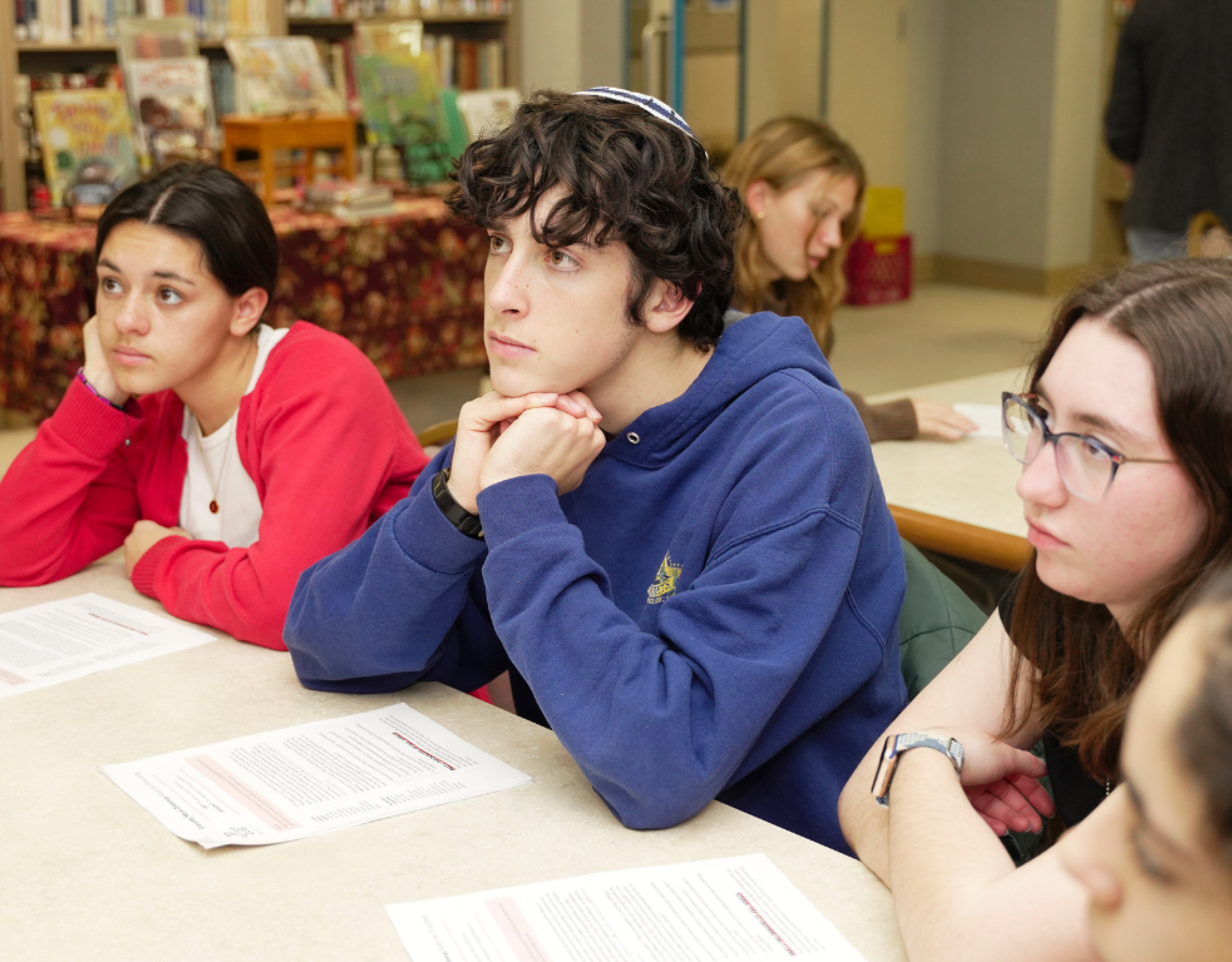 Three teens in thought sitting at a desk
