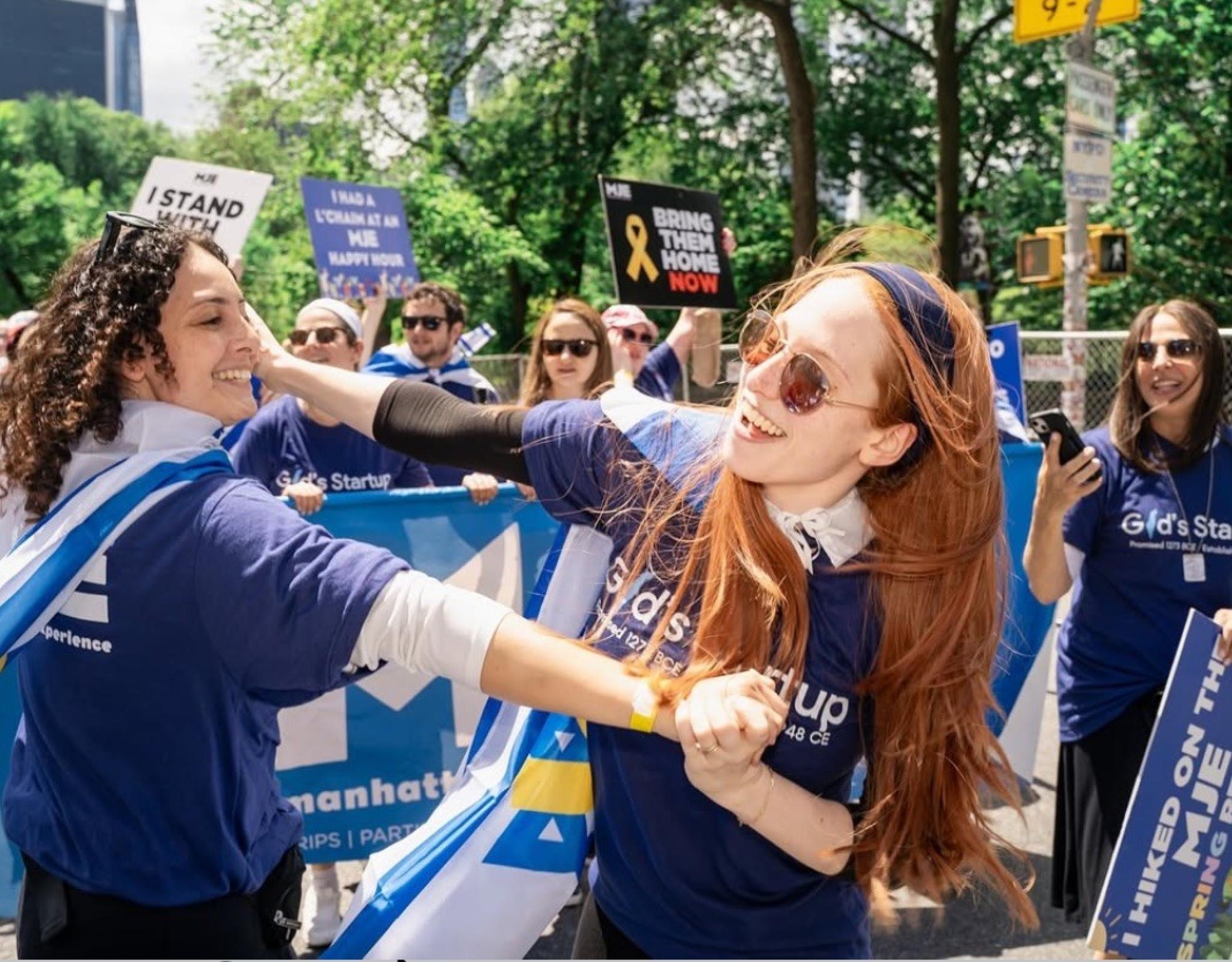 two girls dancing with israeli flags tied around them