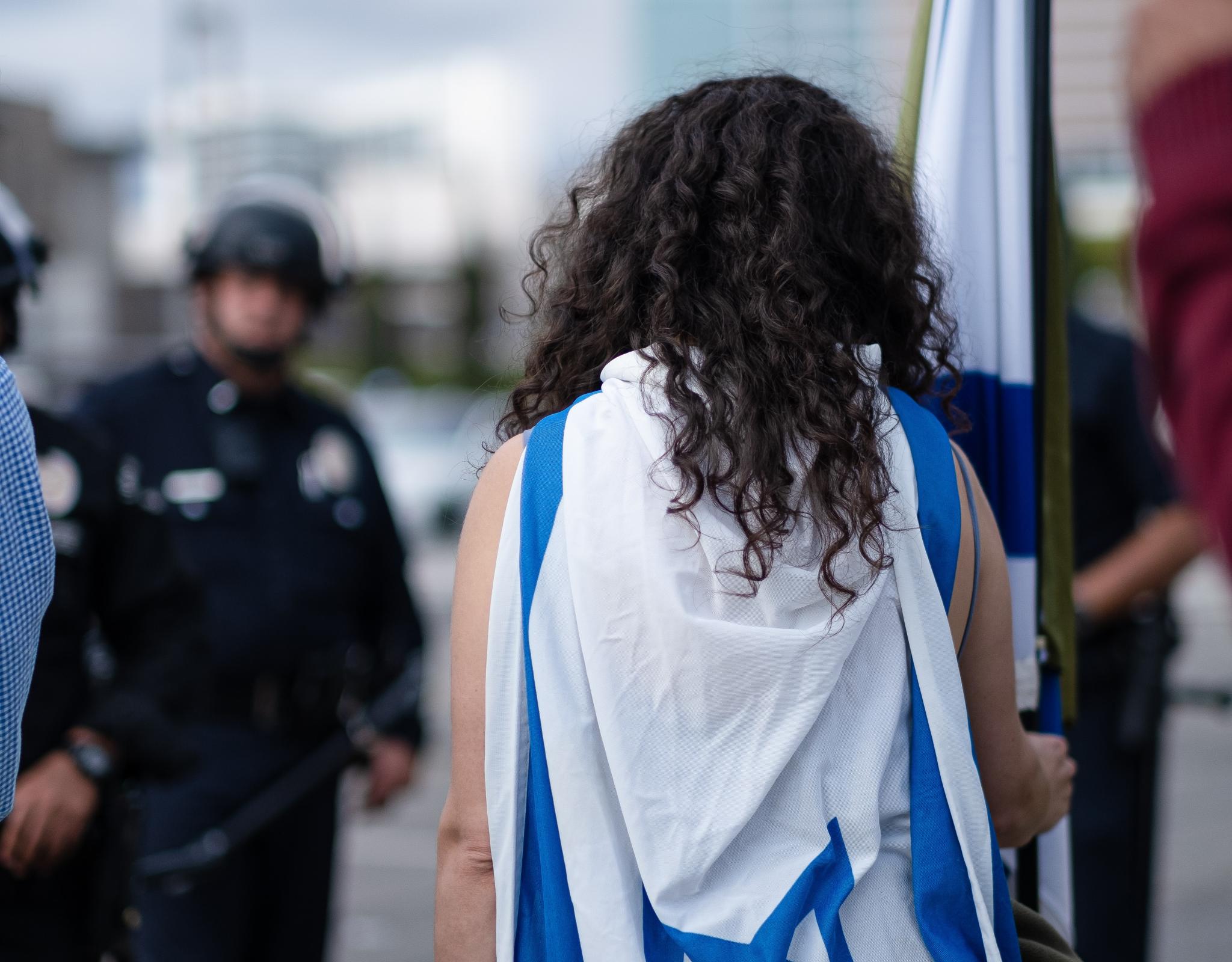 Person with an Israeli flag on their back and holding an Israeli flag 