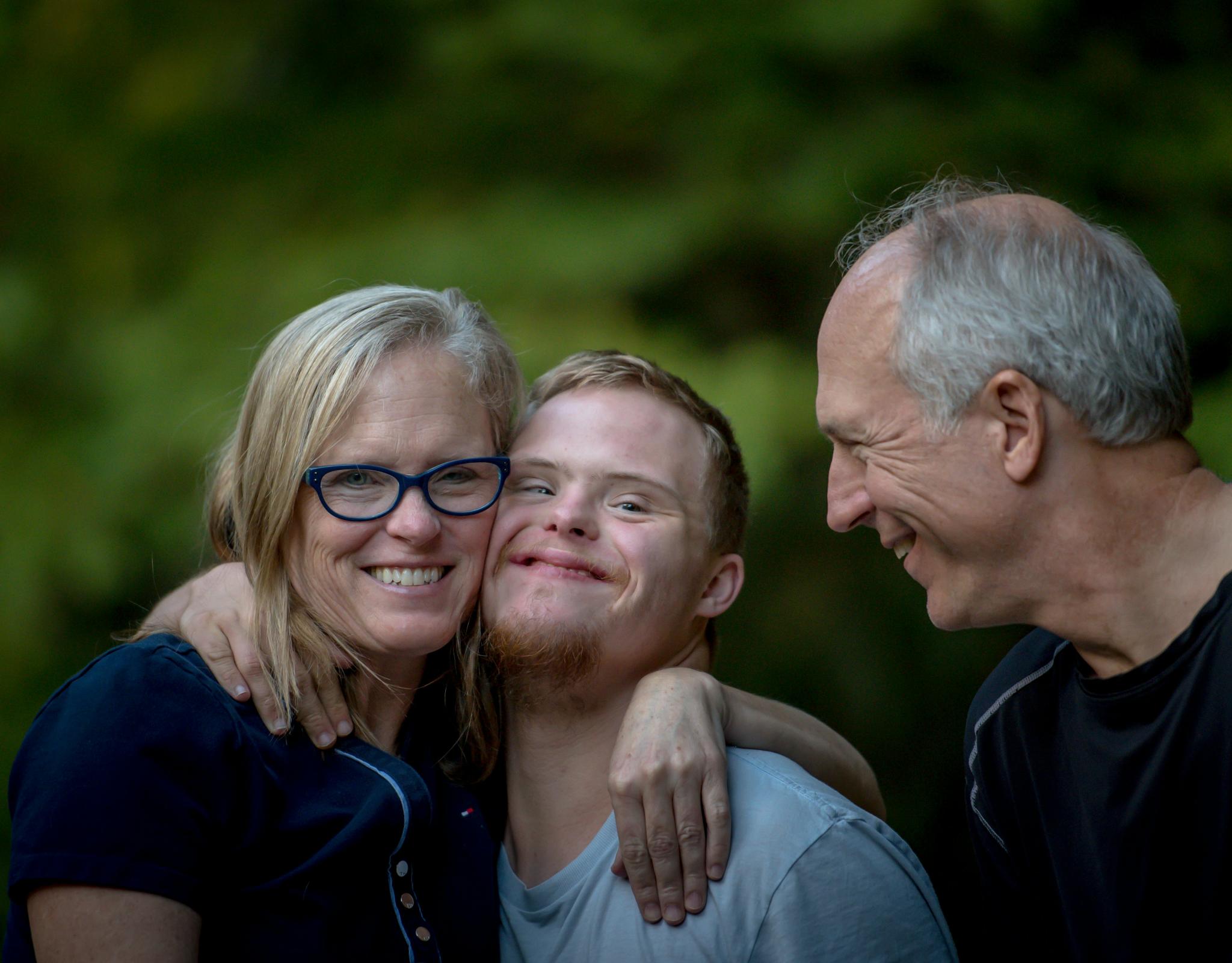 two parents hug their son with Down Syndrome