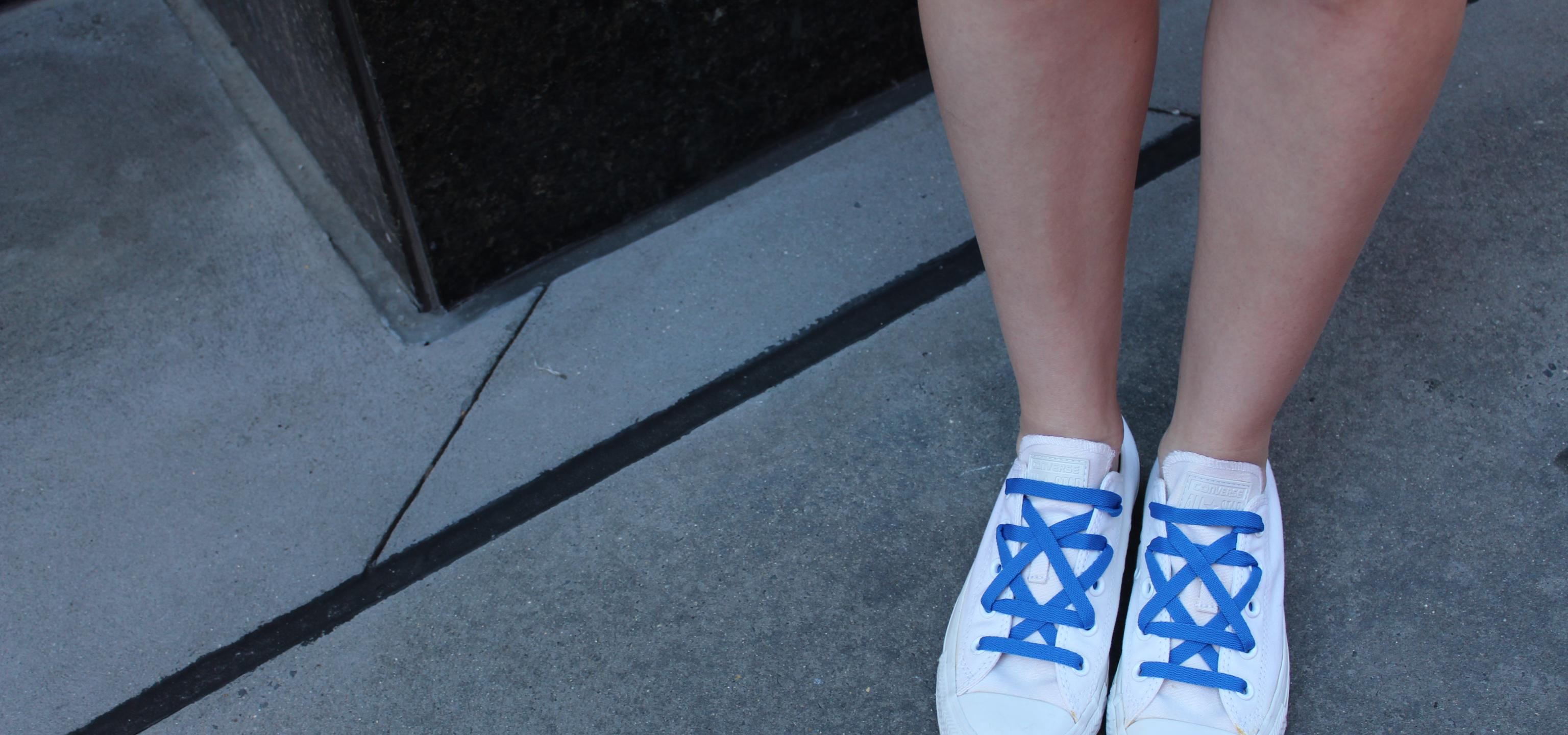 A picture of someone wearing white converse, with royal blue laces arranged in a Jewish star.