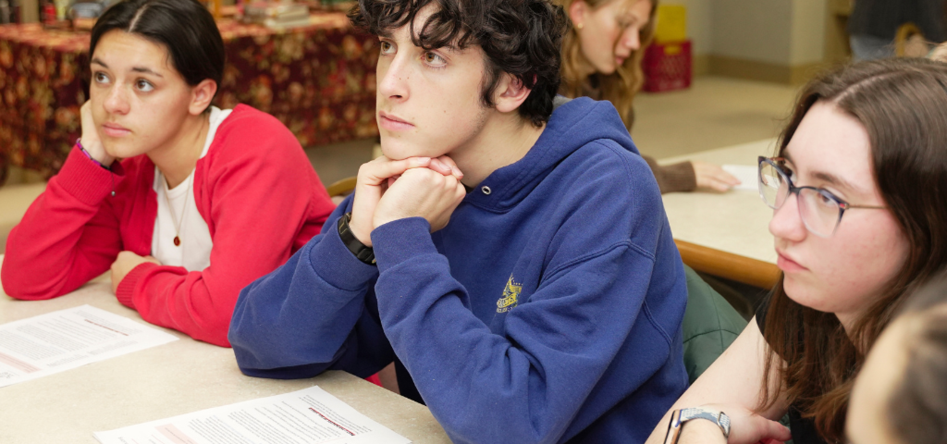 Three teens in thought sitting at a desk