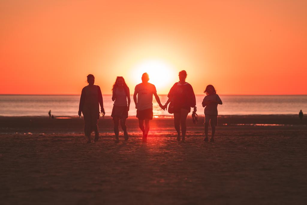 family walking on a beach at sunset 