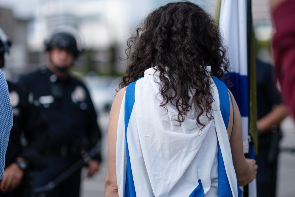 Person with an Israeli flag on their back and holding an Israeli flag 