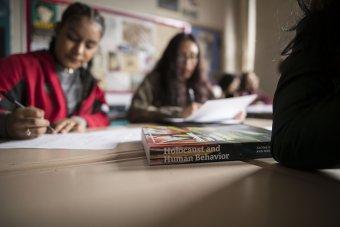 Students in a classroom with a book about the Holocaust