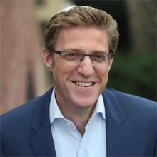 Rabbi Mark Wildes headshot in suit and tie and kippah smiling
