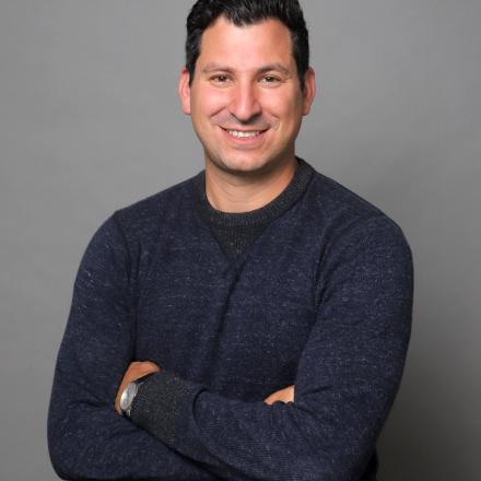 A photo of Dr. Noam Weissman in front of a grey background. 