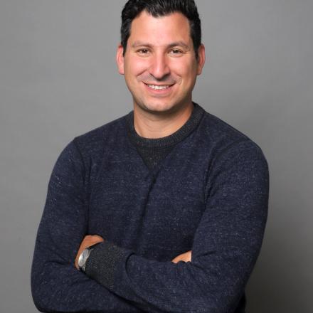 A photo of Dr. Noam Weissman in front of a grey background.