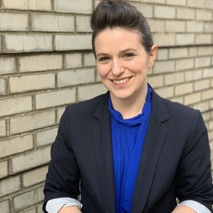 A headshot of Jaimie in front of a brick wall. 