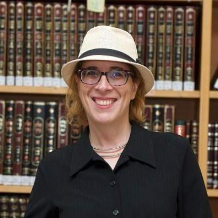A headshot of Nechama Goldman Barash in front of a bookshelf.