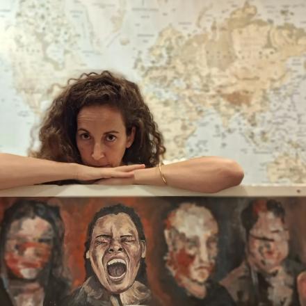 A headshot of Maya Yehezkel over an artwork.