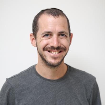 A headshot of Ayal Beer in front of a grey background.