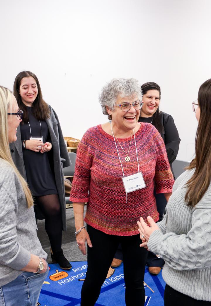 Facilitator in discussion with adult participants, everyone smiling. 